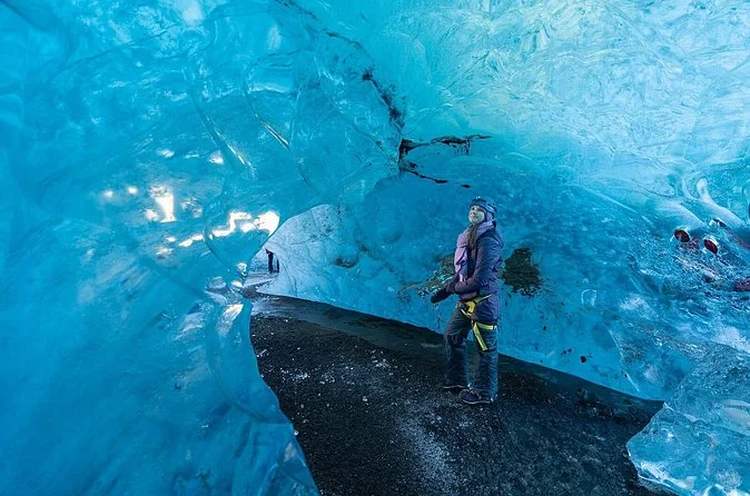 Una grotta di ghiaccio Vatnajökull blu brillante con una persona all'interno