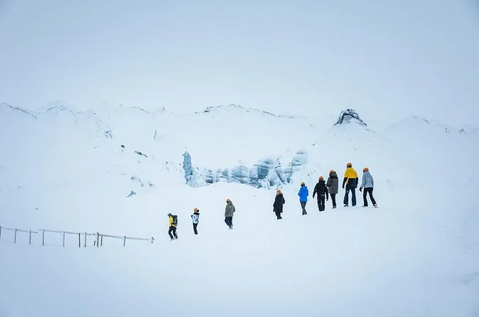 A group walking in a line across a snowy glacier in winter